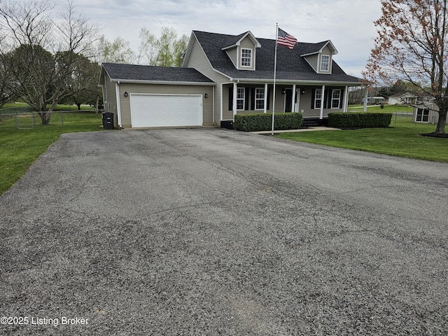 new england style home with a front lawn, aphalt driveway, fence, covered porch, and an attached garage