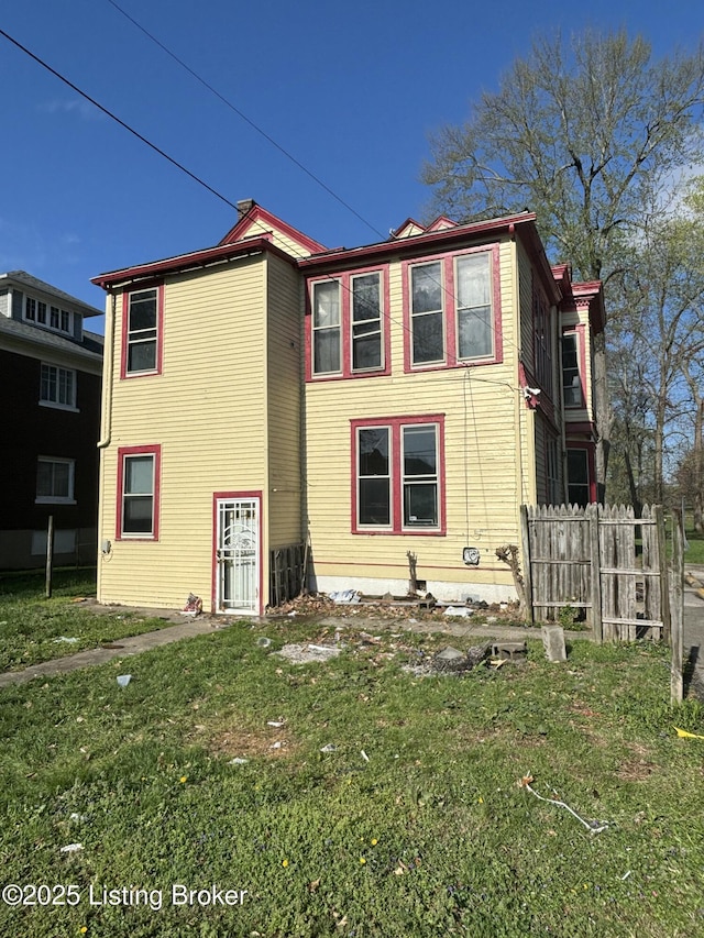 rear view of house featuring a yard and fence