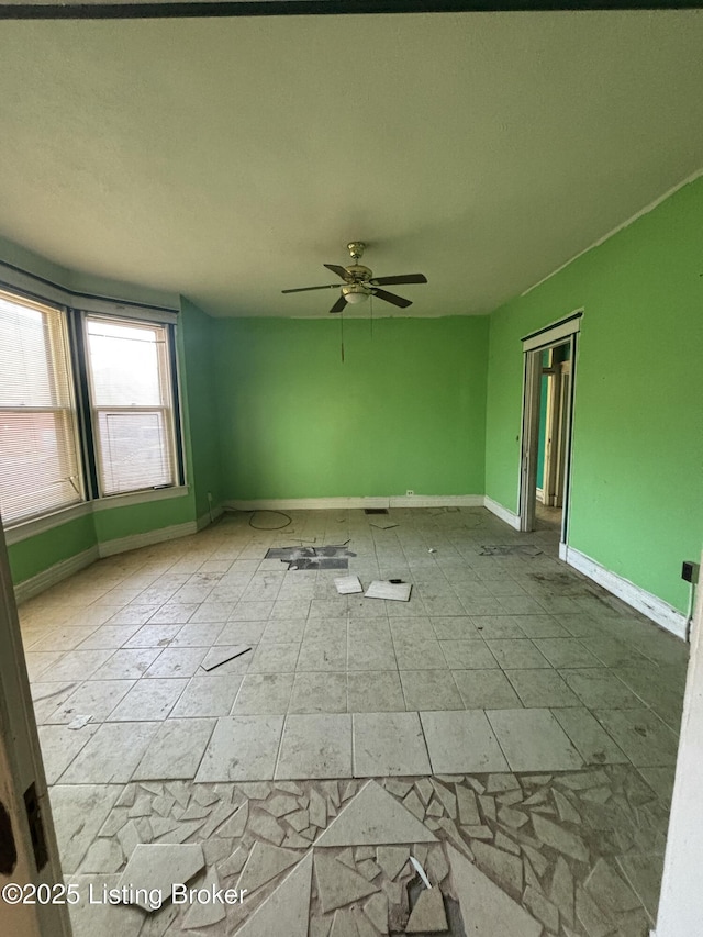 empty room with ceiling fan and baseboards