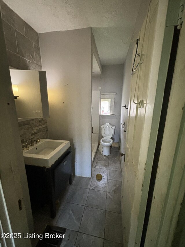 half bath with toilet, vanity, and a textured ceiling