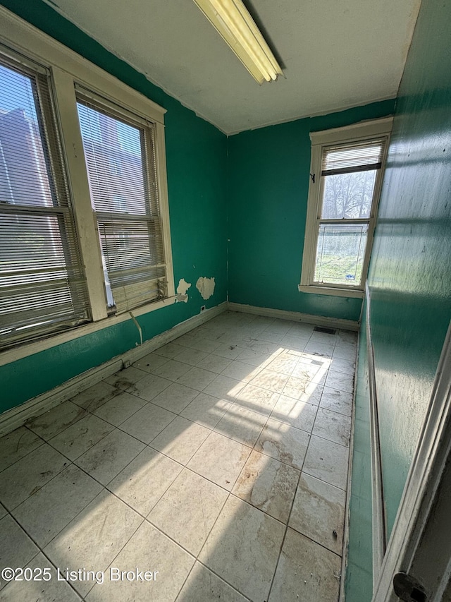 tiled spare room featuring baseboards