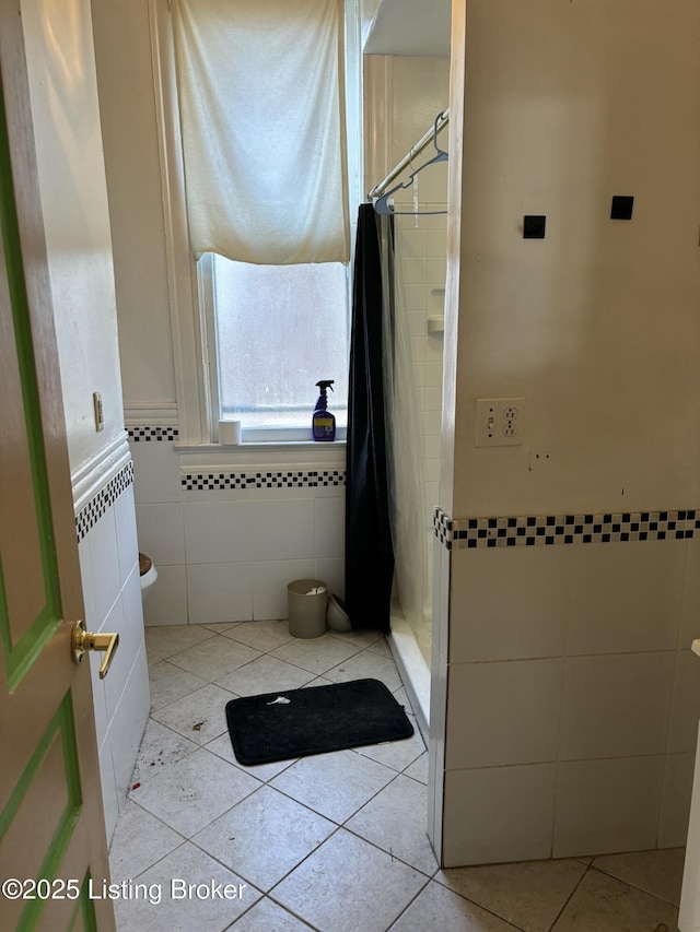full bath with tile walls, a shower stall, and tile patterned flooring