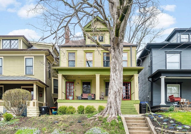 american foursquare style home with covered porch and a chimney