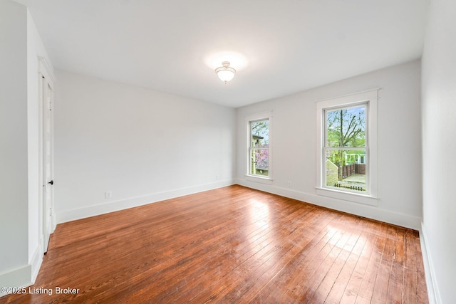 unfurnished room with hardwood / wood-style flooring and baseboards