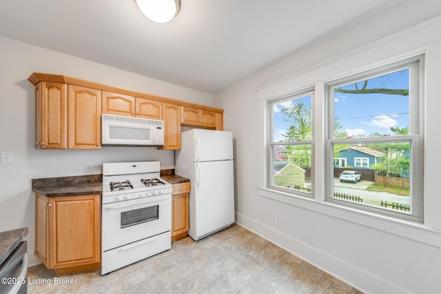 kitchen featuring baseboards and white appliances