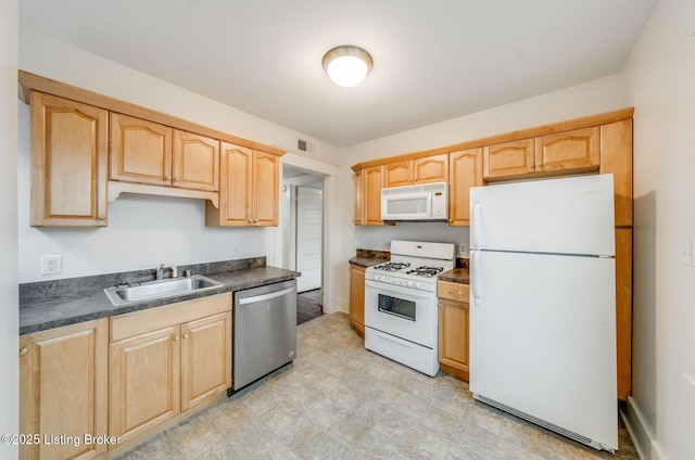 kitchen with white appliances, dark countertops, visible vents, a sink, and light brown cabinetry
