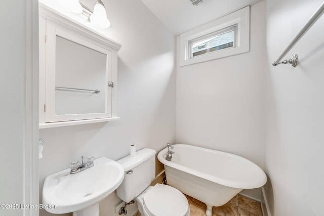 bathroom featuring a freestanding bath, a sink, and toilet