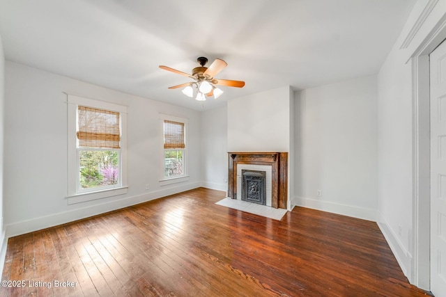 unfurnished living room with a fireplace with flush hearth, baseboards, hardwood / wood-style floors, and a ceiling fan