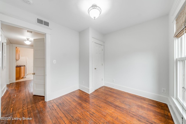 spare room featuring baseboards, dark wood-style floors, and visible vents