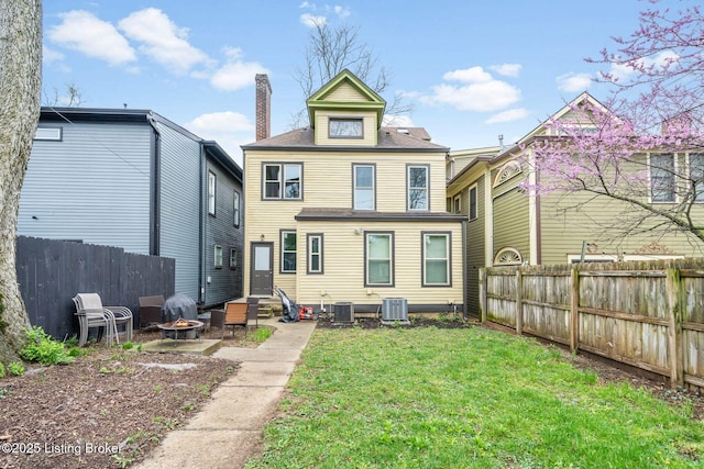 rear view of house with a chimney, cooling unit, an outdoor fire pit, a yard, and fence