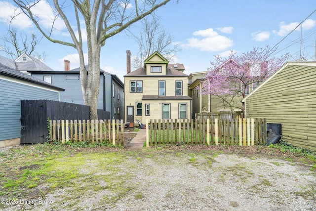 rear view of house with a chimney and fence
