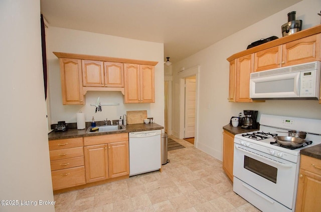 kitchen with white appliances, light brown cabinets, a sink, and dark countertops