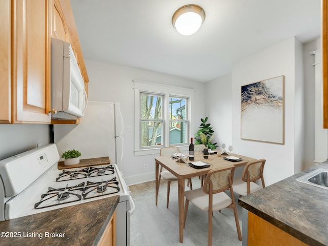 kitchen featuring light wood-style flooring, white appliances, baseboards, and light brown cabinets