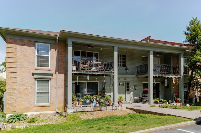 rear view of property with brick siding, ceiling fan, and a balcony