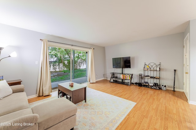 living area featuring baseboards and light wood finished floors