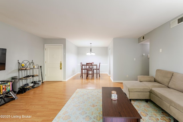 living room with visible vents, baseboards, an inviting chandelier, and light wood finished floors