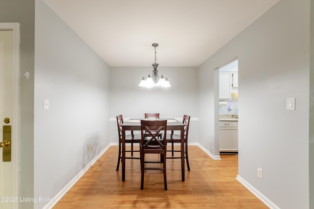 dining area with baseboards, a chandelier, and light wood-style floors