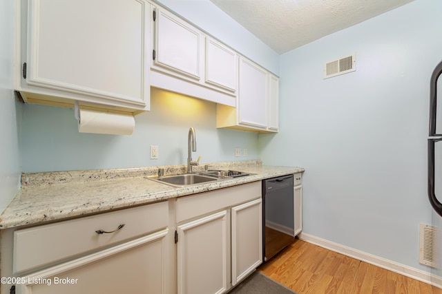 kitchen featuring a sink, dishwasher, light wood-style flooring, baseboards, and visible vents