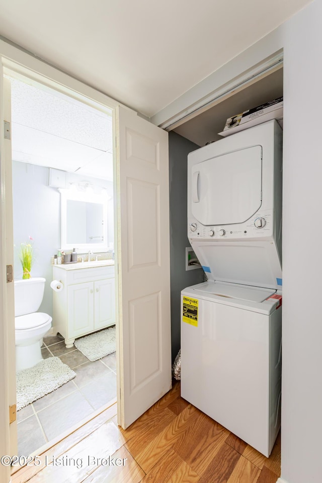 laundry room with stacked washing maching and dryer, laundry area, and a sink