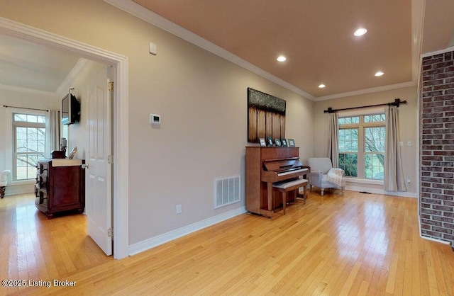 living area featuring baseboards, visible vents, light wood finished floors, and a wealth of natural light