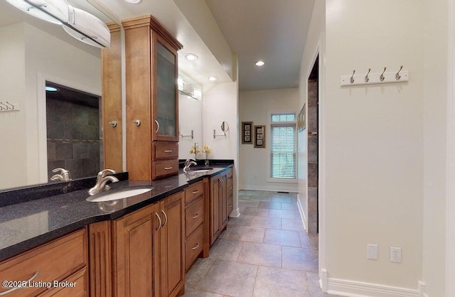 bathroom with baseboards, a sink, double vanity, and recessed lighting