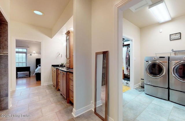 laundry room with washing machine and dryer, baseboards, light tile patterned flooring, and laundry area