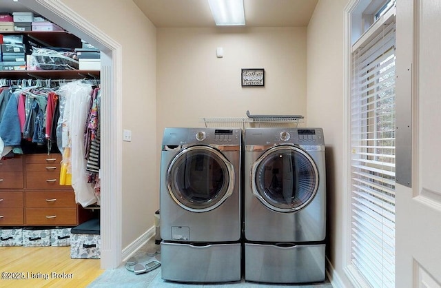 clothes washing area with baseboards, wood finished floors, washer and dryer, and laundry area