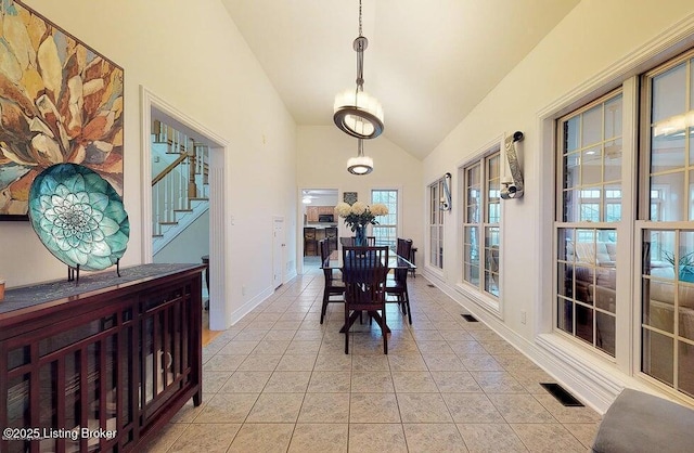 dining room with baseboards, visible vents, high vaulted ceiling, and light tile patterned floors