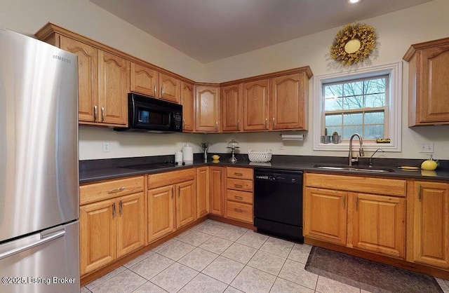 kitchen featuring a sink, light tile patterned flooring, dark countertops, brown cabinetry, and black appliances