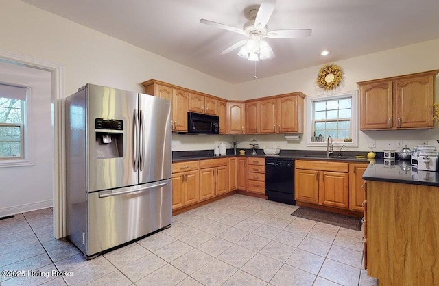 kitchen with dark countertops, light tile patterned floors, a sink, and black appliances