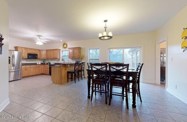 dining area with ceiling fan with notable chandelier, baseboards, and light tile patterned floors