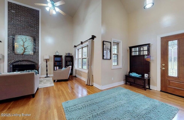 foyer entrance featuring baseboards, wood finished floors, a ceiling fan, and high vaulted ceiling