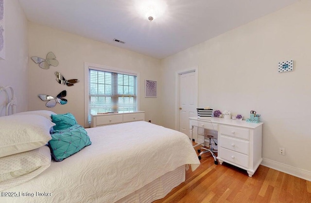 bedroom with light wood-style floors, visible vents, and baseboards