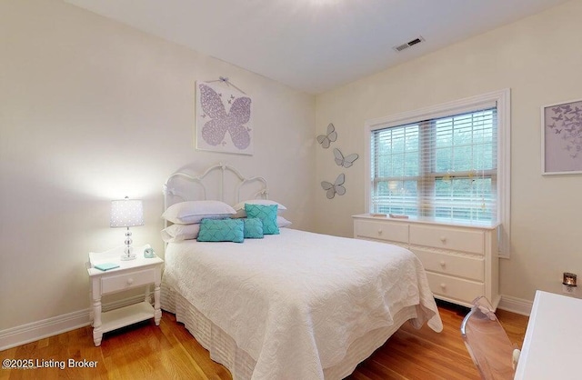 bedroom with baseboards, wood finished floors, and visible vents