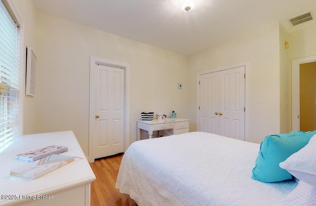 bedroom featuring light wood-style flooring, visible vents, and a closet