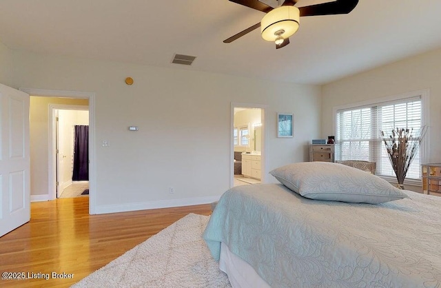bedroom featuring baseboards, visible vents, light wood-style floors, a ceiling fan, and ensuite bath