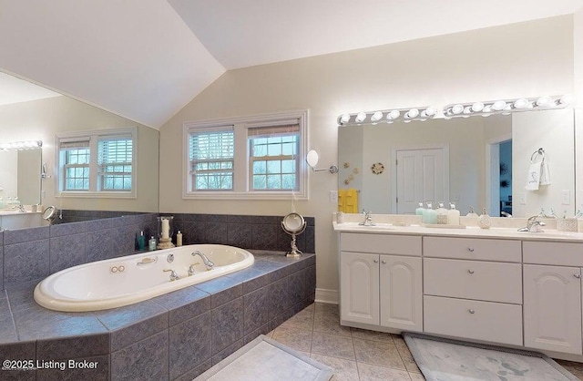 full bathroom featuring double vanity, a bath, tile patterned flooring, and a sink