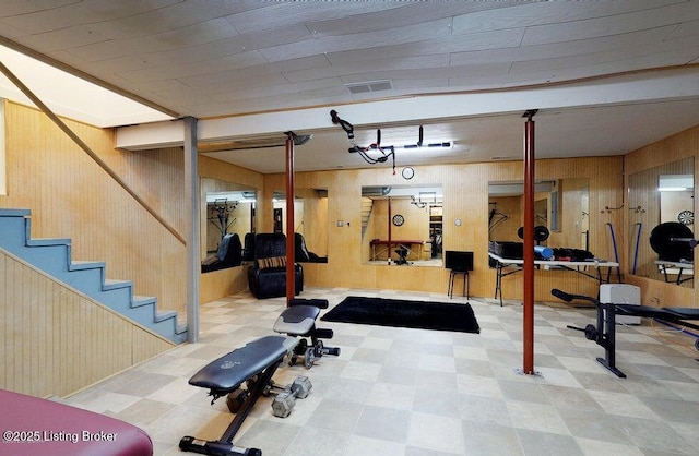 workout area with visible vents, tile patterned floors, and wooden walls