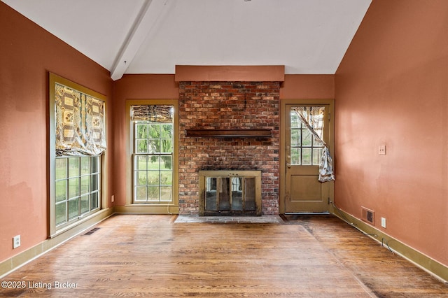 unfurnished living room with visible vents, vaulted ceiling with beams, and wood finished floors