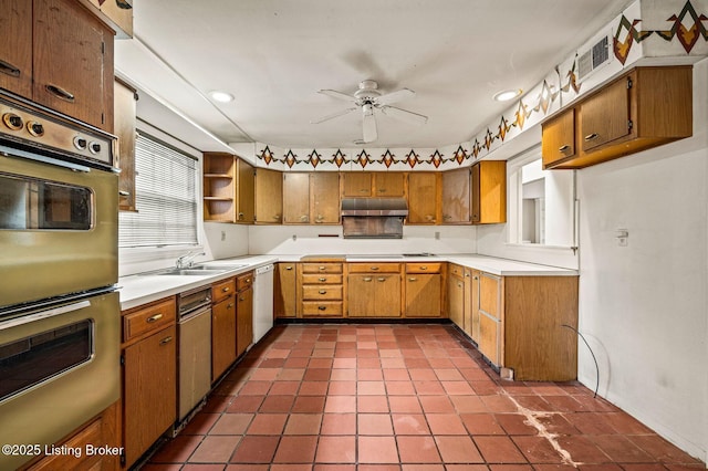 kitchen featuring dishwasher, a sink, multiple ovens, a ceiling fan, and under cabinet range hood