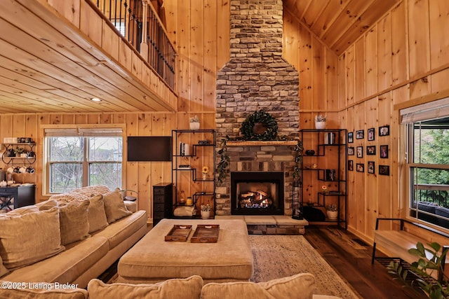 living room featuring high vaulted ceiling, a stone fireplace, wood ceiling, wooden walls, and wood-type flooring