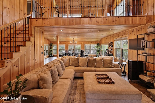 living room with a chandelier, a high ceiling, wood walls, and stairway