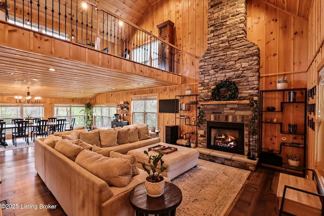 living area featuring wooden ceiling, a notable chandelier, a towering ceiling, wood walls, and hardwood / wood-style floors