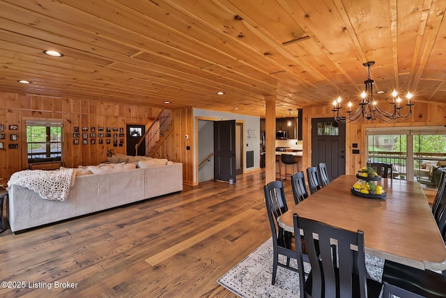 dining room featuring a wealth of natural light, stairway, wood ceiling, wood walls, and a notable chandelier