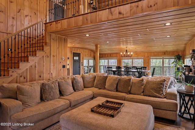 living room with wood walls, stairway, wooden ceiling, and an inviting chandelier