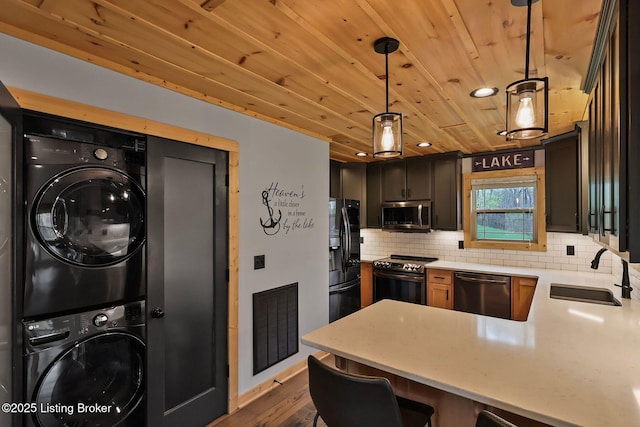 kitchen with visible vents, wood ceiling, appliances with stainless steel finishes, a sink, and stacked washing maching and dryer
