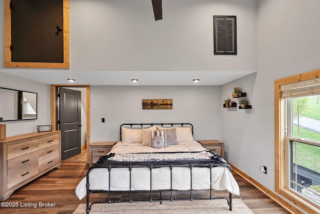 bedroom featuring a high ceiling, wood finished floors, baseboards, and visible vents