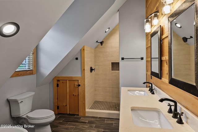 full bathroom featuring tiled shower, wood finish floors, a sink, and vaulted ceiling