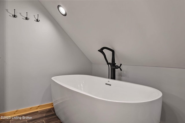 details with baseboards, a freestanding tub, and wood finished floors