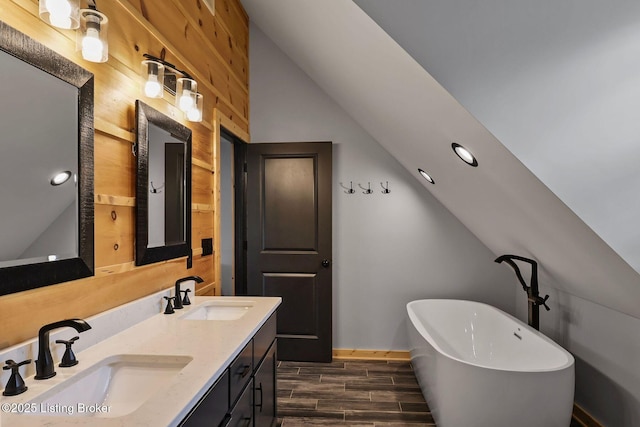full bathroom featuring wood finished floors, vaulted ceiling, a sink, and a soaking tub